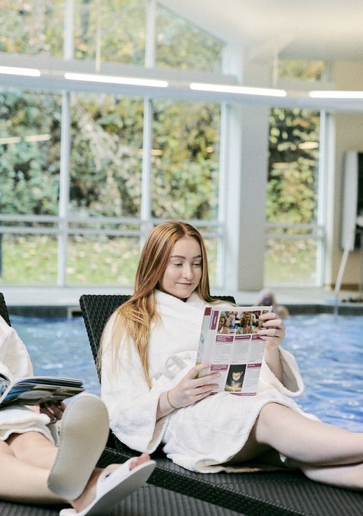 two girls sitting on chairs near the pool